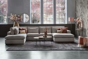 Lichte hoekbank Annabelle Square met ronde salontafels en een groot vloerkleed.