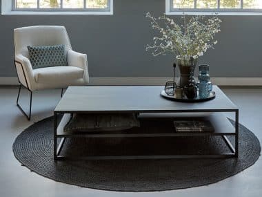 Zwarte Heavy Metal Coffeetable 140cm, met boucle fauteuil en rond vloerkleed.