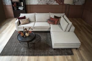 Hoekbank Nadine met dubbele rug- en zitkussens in een beige stof, in een sfeervol interieur.