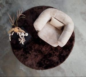 beige fauteuil met ronde en organische vormen in de armleuning, rugleuning en zitting. Gestyled met natuurlijke materialen en beige en zwarte woonaccessoires.