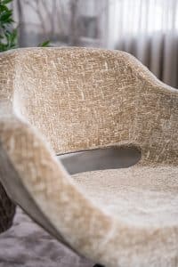 Beige eetkamerstoel met een zwart onderstel en een kuipzitting