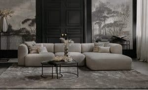 Elementenbank Emanuelle met een longchair. Uitgevoerd in een lichte beige stof. Gecombineerd met een groot vloerkleed en naturel decoratie.