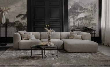 Elementenbank Emanuelle met een longchair. Uitgevoerd in een lichte beige stof. Gecombineerd met een groot vloerkleed en naturel decoratie.