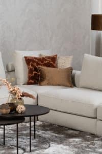 Beige bank met verschillende elementen en een sfeervolle rood / roze interieurstyling.