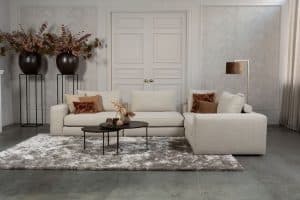 Beige bank met verschillende elementen en een sfeervolle rood / roze interieurstyling.