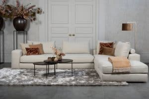 Beige bank met verschillende elementen en een sfeervolle rood / roze interieurstyling.