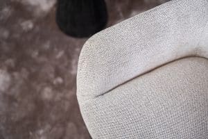 Detail van lichte natural eetkamerstoel met armleuning.
