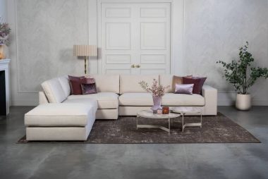 Beige hoekbank met grote hoek, gestyled met woonaccessoires in Burgundy.