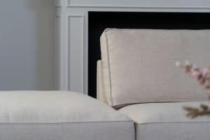 Beige hoekbank met grote hoek, gestyled met woonaccessoires in Burgundy.