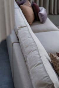 Beige hoekbank met grote hoek, gestyled met woonaccessoires in Burgundy.