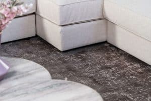 Beige hoekbank met grote hoek, gestyled met woonaccessoires in Burgundy.