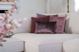 Beige hoekbank met grote hoek, gestyled met woonaccessoires in Burgundy.