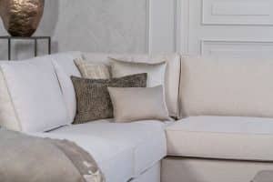 Lichte beige hoekbank met bruine woonaccessoires.