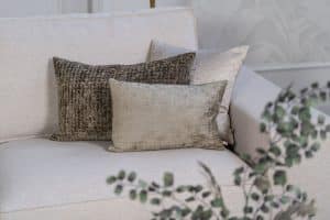 Lichte beige hoekbank met bruine woonaccessoires.