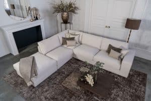 Lichte beige hoekbank met bruine woonaccessoires.