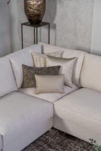 Lichte beige hoekbank met bruine woonaccessoires.
