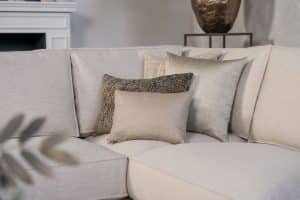 Lichte beige hoekbank met bruine woonaccessoires.