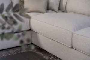 Lichte beige hoekbank met bruine woonaccessoires.