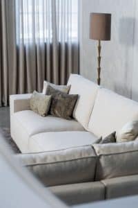 Lichte beige hoekbank met bruine woonaccessoires.