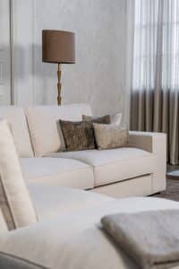 Lichte beige hoekbank met bruine woonaccessoires.