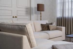 Lichte beige hoekbank met bruine woonaccessoires.