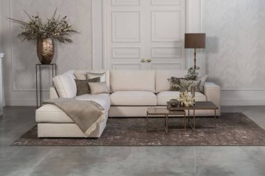 Lichte beige hoekbank met bruine woonaccessoires.