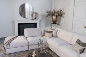 Lichte beige hoekbank met bruine woonaccessoires.