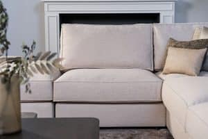 Lichte beige hoekbank met bruine woonaccessoires.