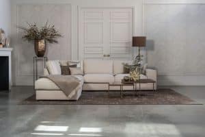 Lichte beige hoekbank met bruine woonaccessoires.