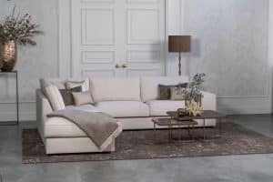 Lichte beige hoekbank met bruine woonaccessoires.