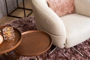 Levi draaifauteuil van Gusj in lichte bouclé stof met draaionderstel op een roze rond vloerkleed in een stijlvol interieur.