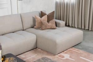 Hoekbank Alix in stof Glory Liver 10 met karakteristieke vakverdeling in de zitvlakken, uitgevoerd in een ruime hoekopstelling met comfortabele loungezijde.