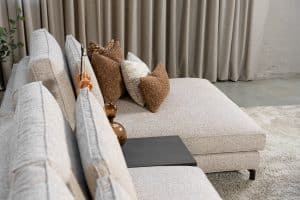 Hoekbank Mila in stof Gautier 7 met slanke metalen poten, losse kussens en een royale loungezijde in een moderne hoekopstelling.