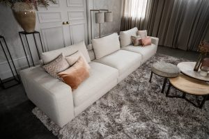 Beige bank met verschillende elementen en een sfeervolle rood / roze interieurstyling.