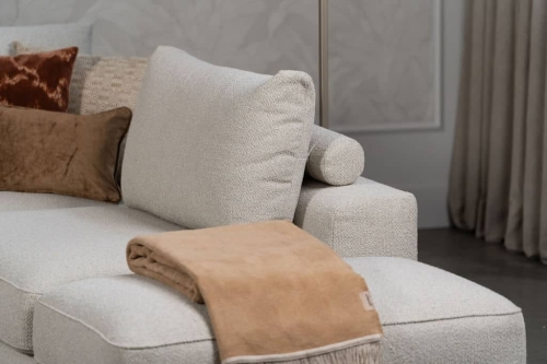 Beige bank met verschillende elementen en een sfeervolle rood / roze interieurstyling.