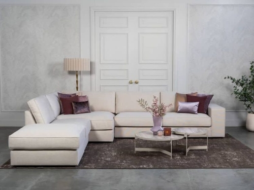 Beige hoekbank met grote hoek, gestyled met woonaccessoires in Burgundy.