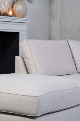 Beige hoekbank met grote hoek, gestyled met woonaccessoires in Burgundy.