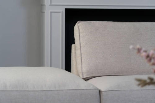 Beige hoekbank met grote hoek, gestyled met woonaccessoires in Burgundy.
