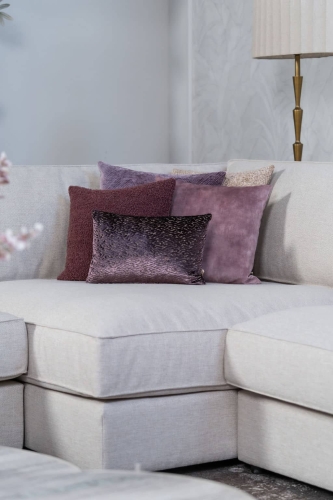 Beige hoekbank met grote hoek, gestyled met woonaccessoires in Burgundy.