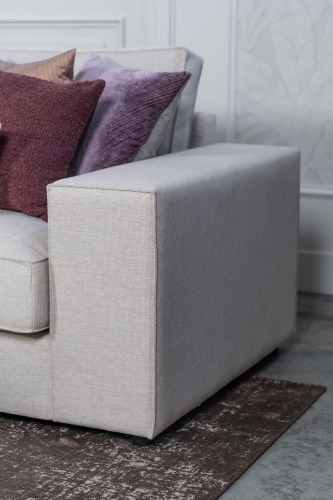 Beige hoekbank met grote hoek, gestyled met woonaccessoires in Burgundy.