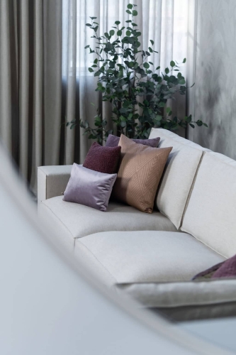 Beige hoekbank met grote hoek, gestyled met woonaccessoires in Burgundy.