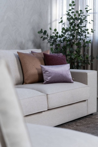 Beige hoekbank met grote hoek, gestyled met woonaccessoires in Burgundy.