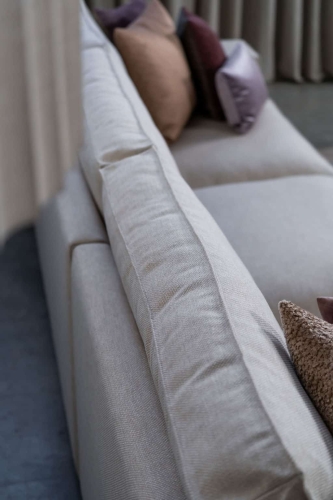 Beige hoekbank met grote hoek, gestyled met woonaccessoires in Burgundy.