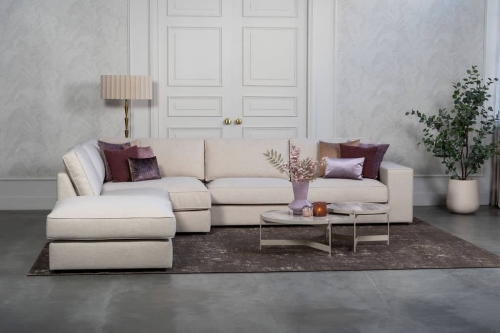 Beige hoekbank met grote hoek, gestyled met woonaccessoires in Burgundy.