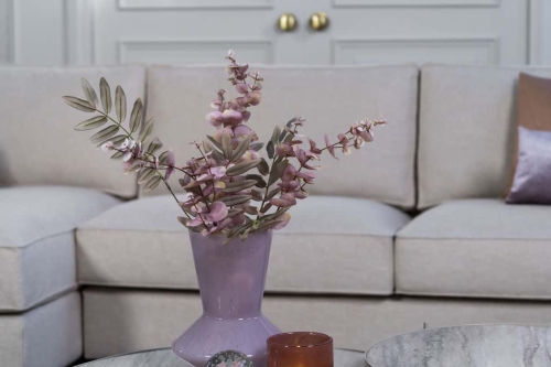 Beige hoekbank met grote hoek, gestyled met woonaccessoires in Burgundy.