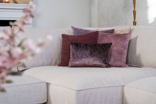 Beige hoekbank met grote hoek, gestyled met woonaccessoires in Burgundy.