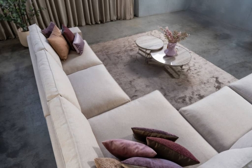 Beige hoekbank met grote hoek, gestyled met woonaccessoires in Burgundy.