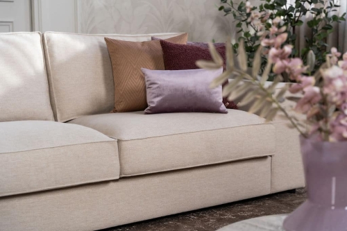 Beige hoekbank met grote hoek, gestyled met woonaccessoires in Burgundy.
