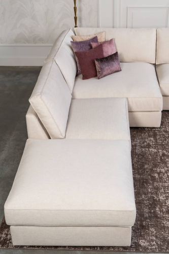 Beige hoekbank met grote hoek, gestyled met woonaccessoires in Burgundy.
