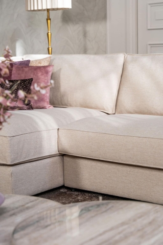 Beige hoekbank met grote hoek, gestyled met woonaccessoires in Burgundy.
